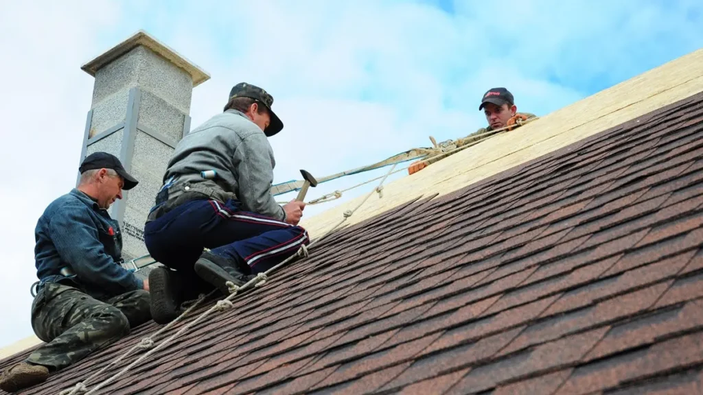 workers installing shingles steep roof chimney