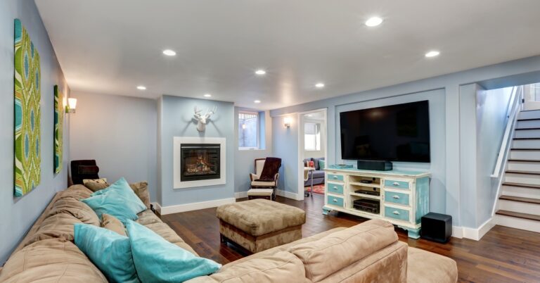 A finished basement with a living area with pastel walls, recessed lighting, an entertainment center, and more.