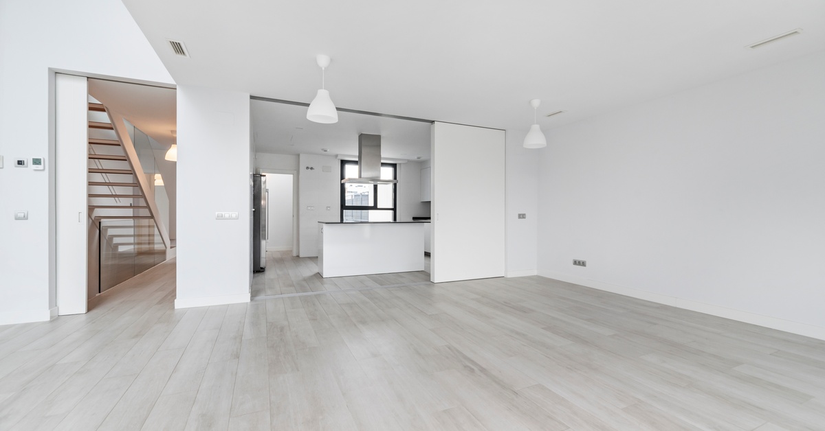 The finished basement of a modern home with an open-plan layout with hanging focused lighting from the ceiling.