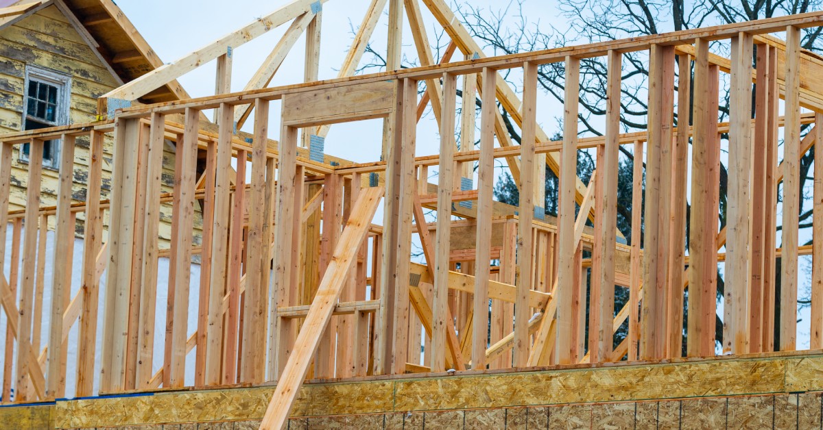 A view of the second floor and roof of a home still under construction with wooden joists and plywood.