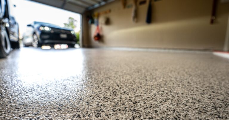 A close-up of the epoxy floor of a residential garage with the door open and a car pulling into the garage.