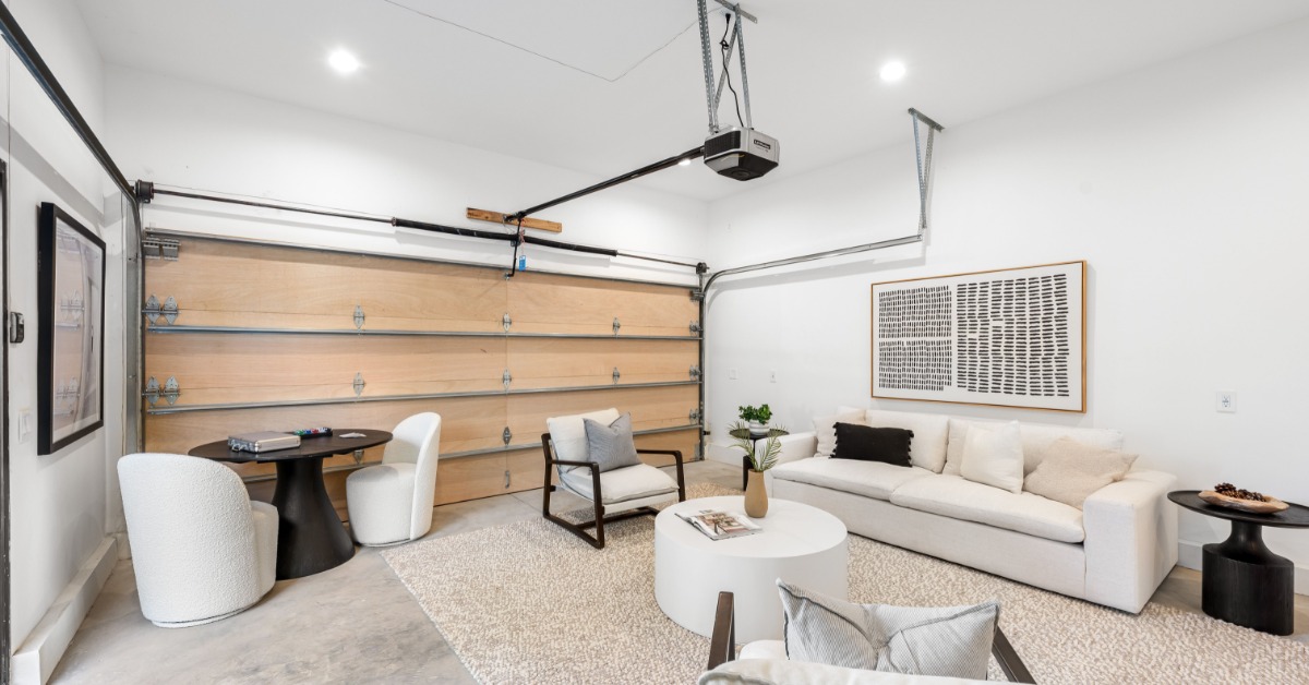 A modern garage that's been transformed into a living space with modern furniture, wall art, and rugs.