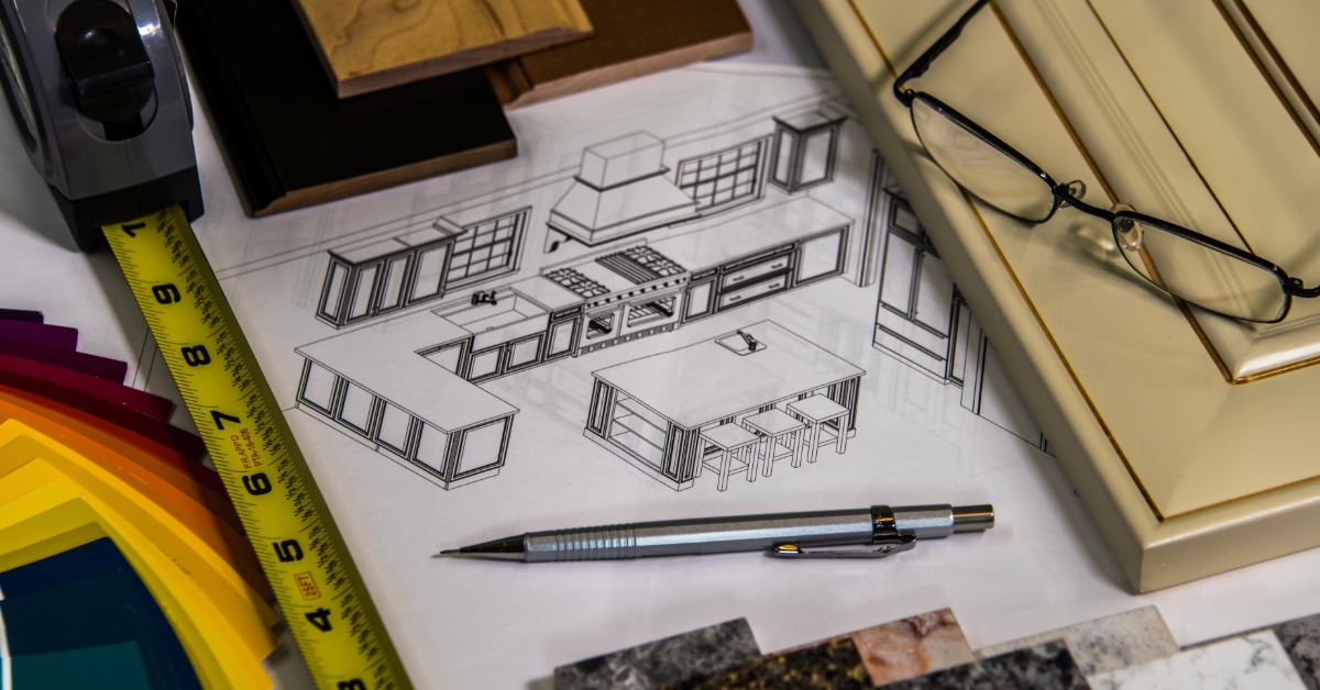A paper with a technical drawing of a home kitchen layout surrounded by a pen, measuring tape, and wood samples.