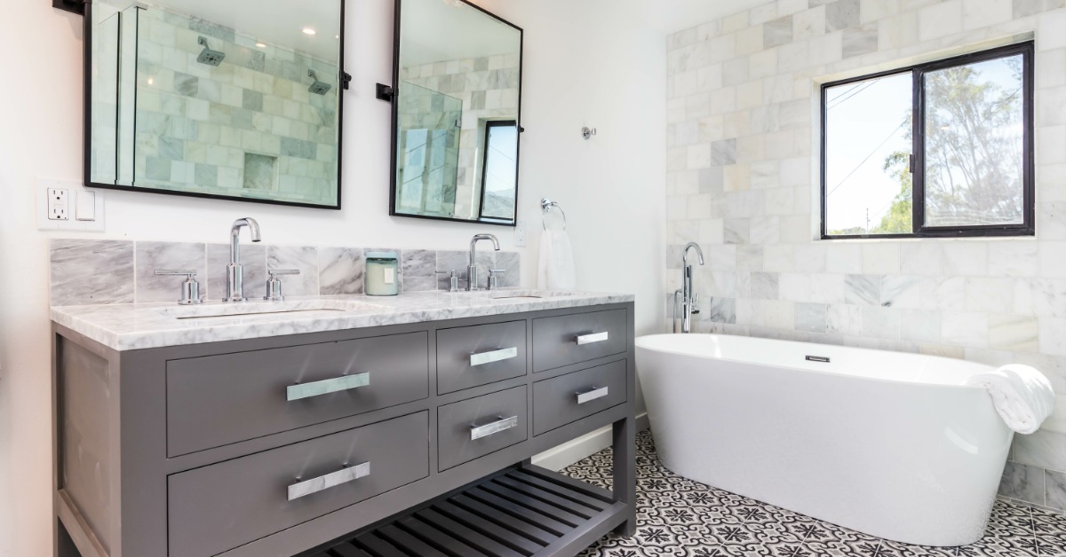 A modern interior bathroom with a bathub, a herringbone tile floor, and a herringbone tile accent wall.