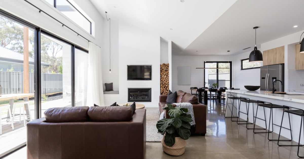 A contemporary home with an open floor plan that includes a sitting room, a kithcen with a large island, and dining nook.