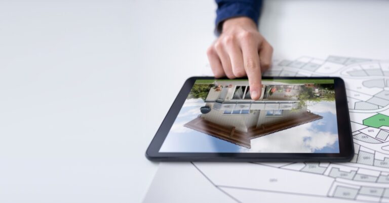 A close-up of a woman using an electronic tablet with a picture of a house while marking a map of land lots with a pencil.