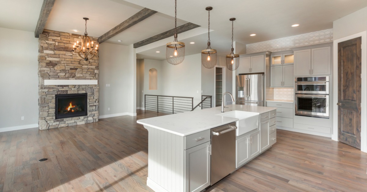 An open-floor plan in a home that combines the kitchen with a living space. The kitchen includes an island with a sink.