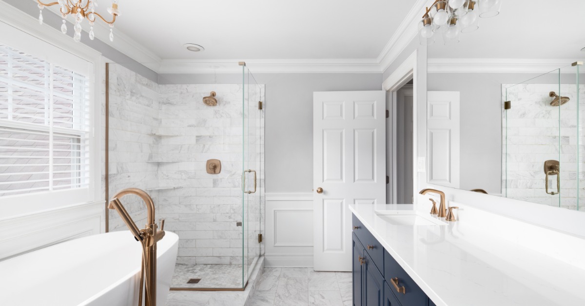 A modern residential bathroom with a tub, a walk-in shower, and a white stone countertop with blue cabinetry.