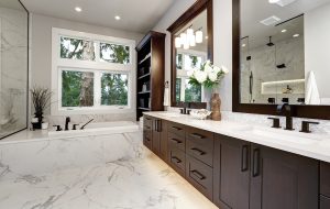 Master bathroom interior in luxury modern home with dark hardwood cabinets, white tub and glass door shower