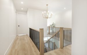 interior hallway with stair case and wrought iron rails blonde hardwood floors and olive tree